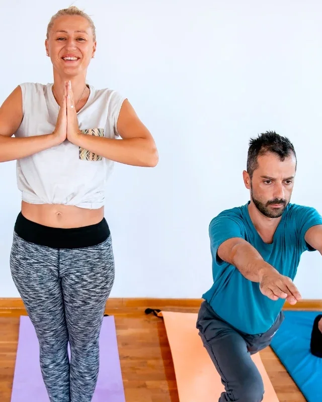 Two adults holding single leg standing balance positions on exercise mats
